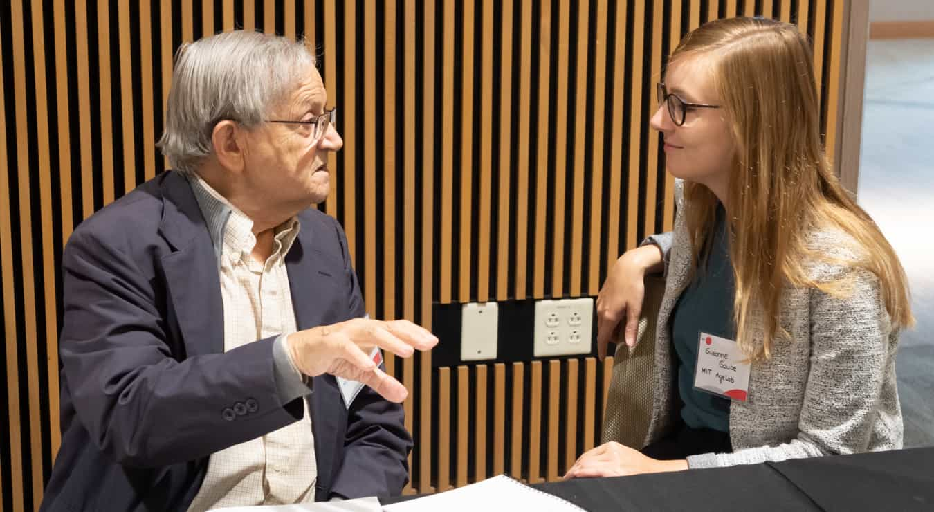 An older gentleman and a woman sitting and talking at a table